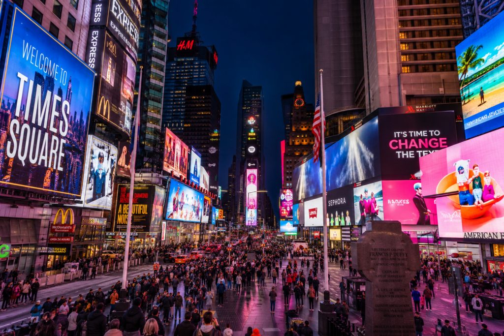Crowds and illuminated billboards in Times Square at night in New York City, one of the world's most famous tourist destinations.